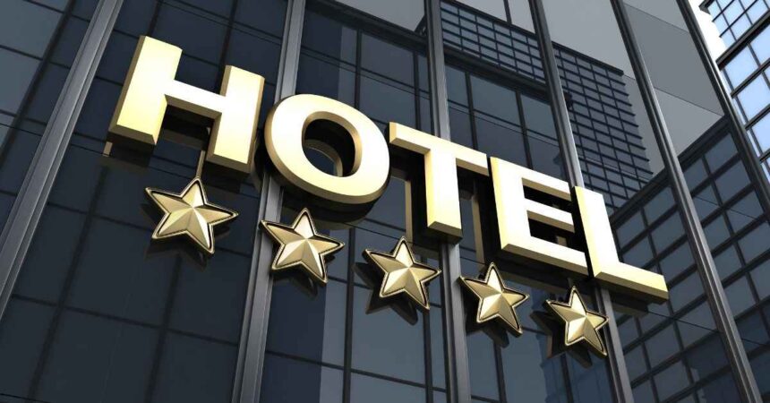 A beautifully made bed in a hotel room with an open balcony showing a city view, demonstrating how to choose the perfect hotel for your vacation