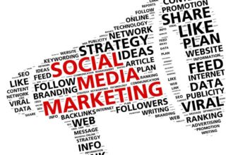 A marketer writing in a social media marketing plan notebook with a laptop and smartphone on the desk.