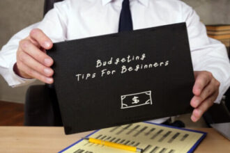 A person at a clean, well-lit desk with a notebook labeled "My Financial Plan," a calculator, a laptop showing a budgeting tips spreadsheet, and a steaming mug of coffee, conveying a sense of calm control.