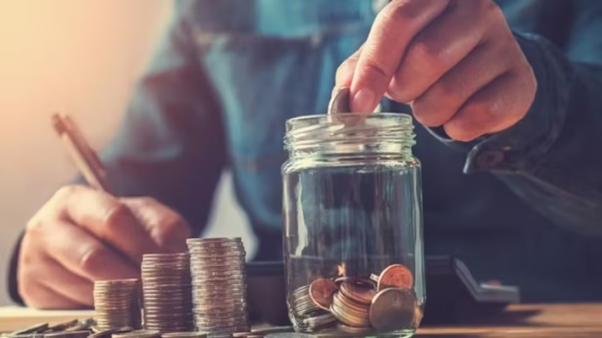 A person carefully placing a coin into a piggy bank, symbolizing the first step to save money on a low income.