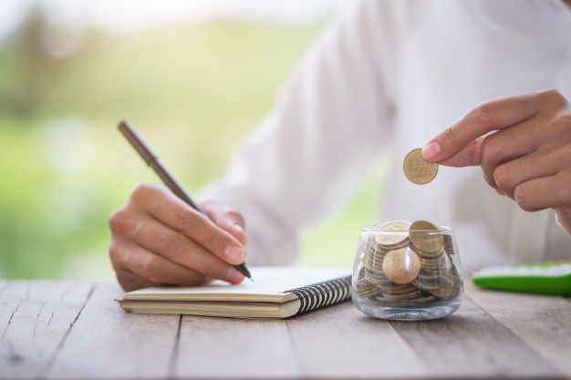 A small, well-tended plant growing out of a single coin, with a large, strong oak tree in the background, symbolizing how small money habits lead to great wealth.