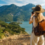 A solo traveler on a journey of self discovery travel, watching the sunrise over mountains.
