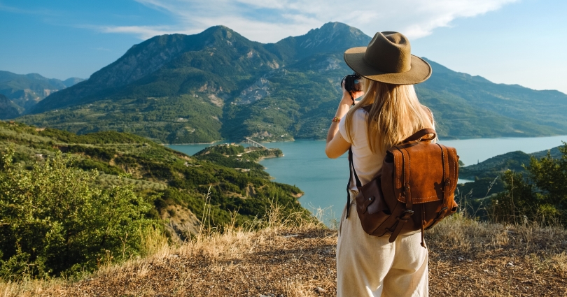 A solo traveler on a journey of self discovery travel, watching the sunrise over mountains.